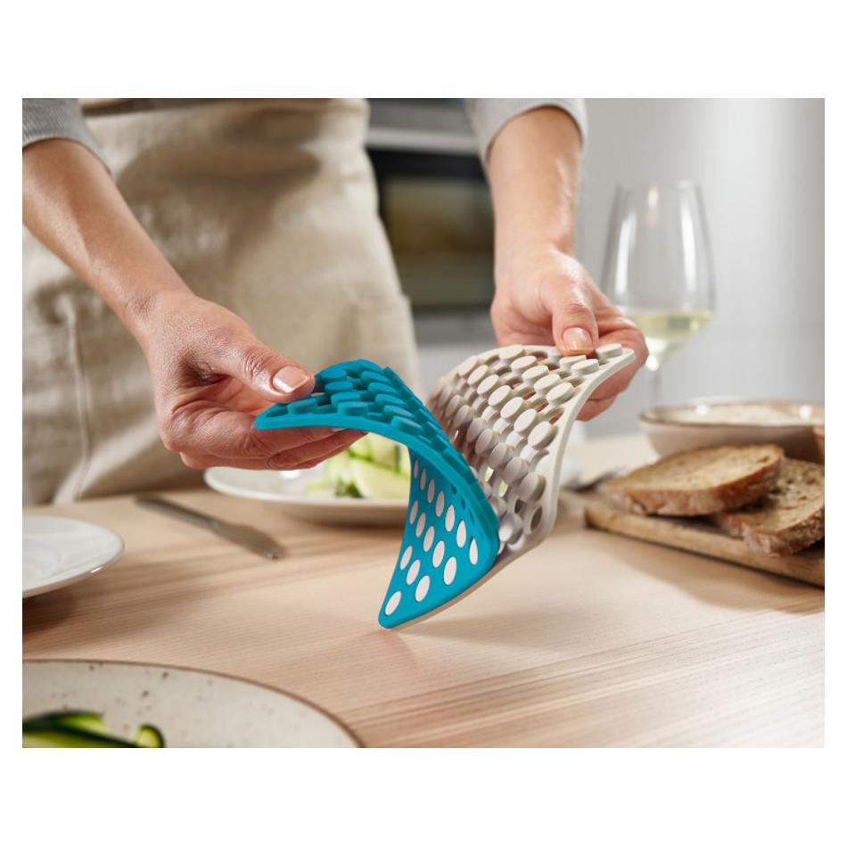 Joseph Joseph Duo silicone trivets flexed by hand to show their soft heat-resistant design