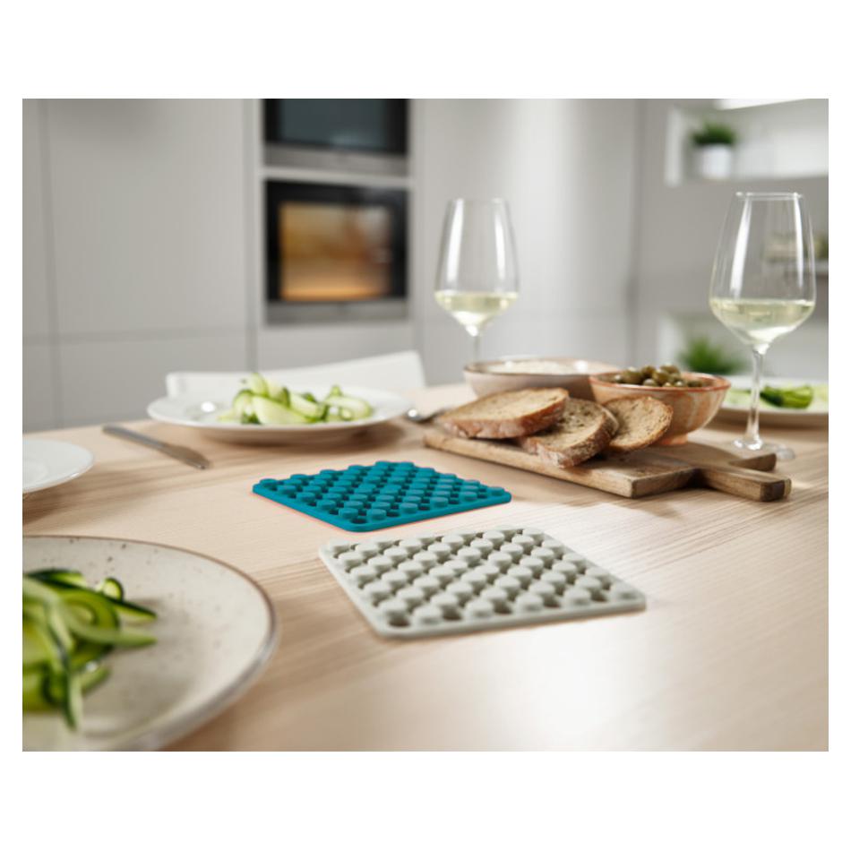 Joseph Joseph Duo Dark Opal and Stone trivets displayed separately on a dining table